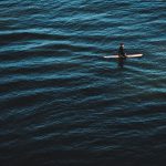 person in black wetsuit surfing on blue sea water during daytime