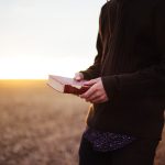 man holding book in the ricefield