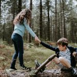 boy and girl playing on three tree log