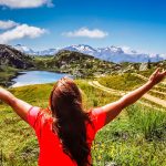 woman in red t-shirt standing on green grass field during daytime