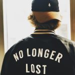 man wearing black letterman jacking facing window