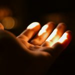 A person holding a lit candle in their hand