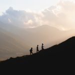 silhouette of 2 people standing on top of mountain during daytime