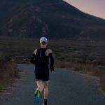 woman jogging on gray road across mountain during daytime