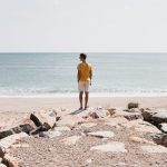 woman in brown shorts standing on rocky shore during daytime