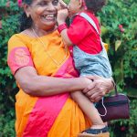 man in red t-shirt carrying girl in gray t-shirt