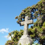 gray cross on gray stone under blue sky during daytime