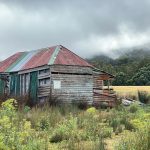 brown wooden house on green grass field under cloudy sky during daytime