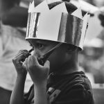 grayscale photography of boy taking off sunglasses