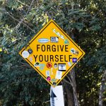 a yellow street sign with stickers on it