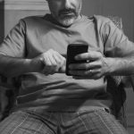A man sitting in a chair looking at his cell phone