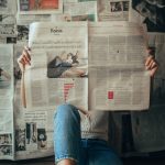 person in blue denim jeans holding white magazine