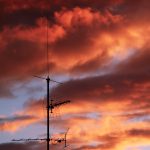 a red sky with clouds and a tv antenna